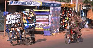 Woman on moped and trader with a sales cart in Burkina Faso